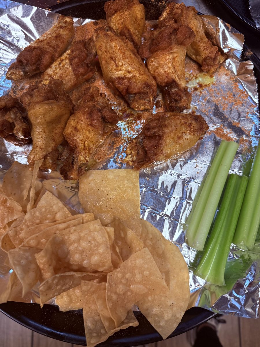 Dry rub wings on foil with tortilla chips and celery